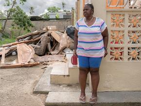 A resident of Loíza, Puerto Rico stands outside her damaged home in the aftermath of Hurricane Maria